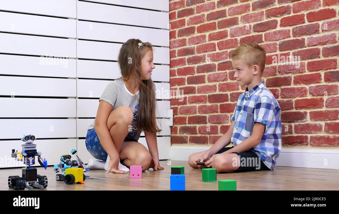 sevenyearold boy and girl play electronic robots, cars, modern toys on the radio control. new