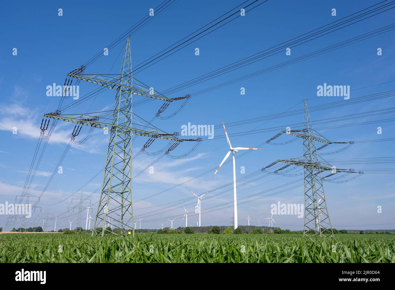 Power lines with wind turbines in the back seen in rural Germany Stock Photo