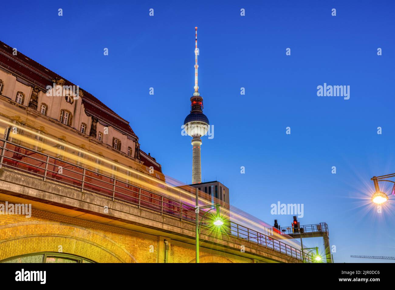 The iconic TV Tower in Berlin at dusk with a motion blurred commuter train Stock Photo