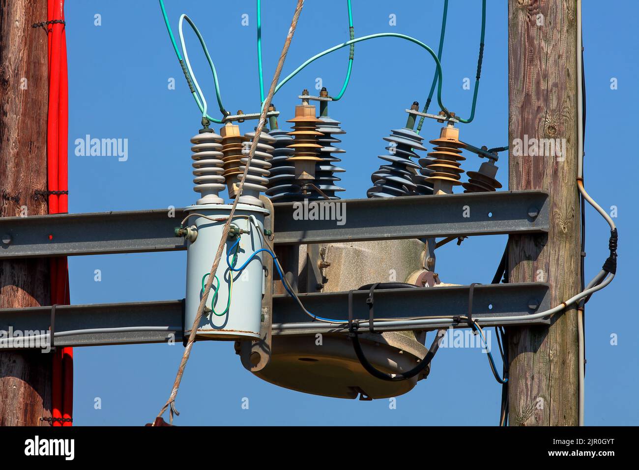 High voltage oil-filled power transformer on electrical substation.Part of  high-voltage substation with switches and dis connectors on blue sky  background Stock-Foto