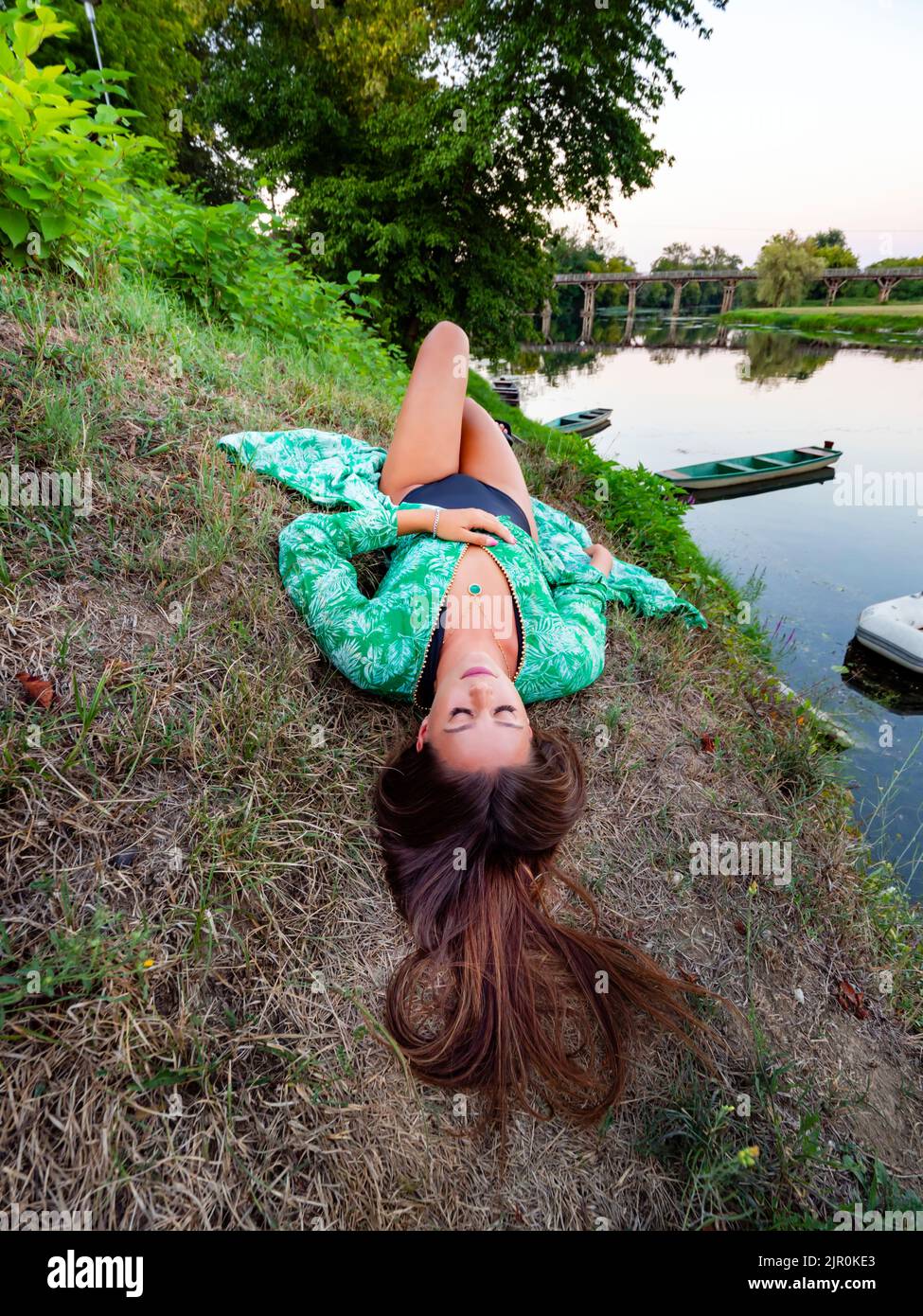 Young woman near calm river riverside outdors nature brunette hair Stock Photo