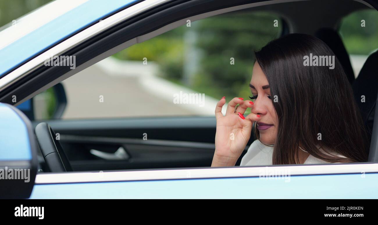 Mature woman feels sick sneezing in car black leather cabin Stock Photo