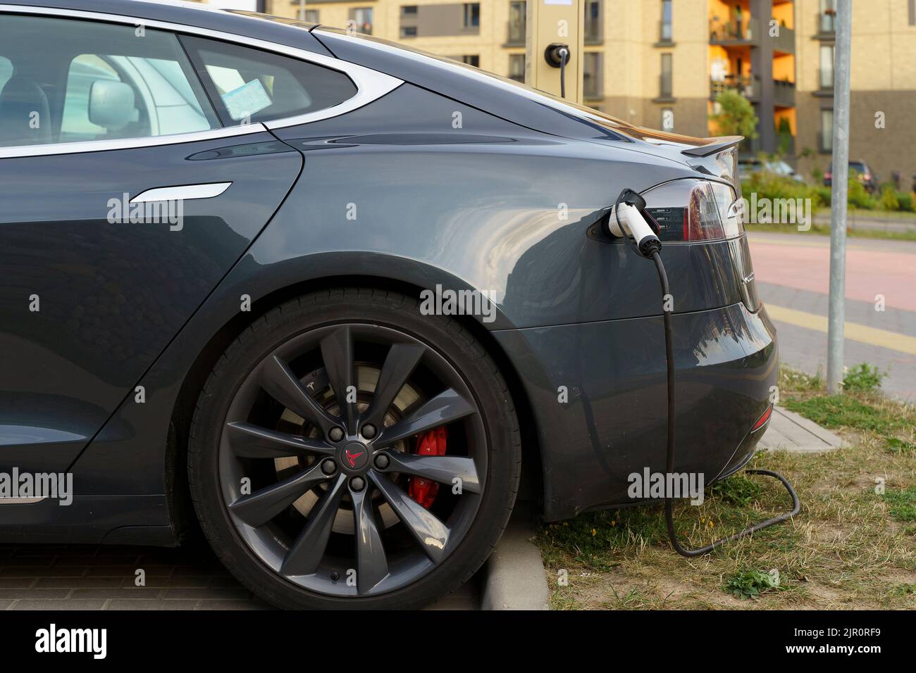 Minsk, Belarus - August 12, 2022: Tesla car charges the electric motor at the charging station on the street. Electric cars, ecology, transport concept. High quality photo Stock Photo