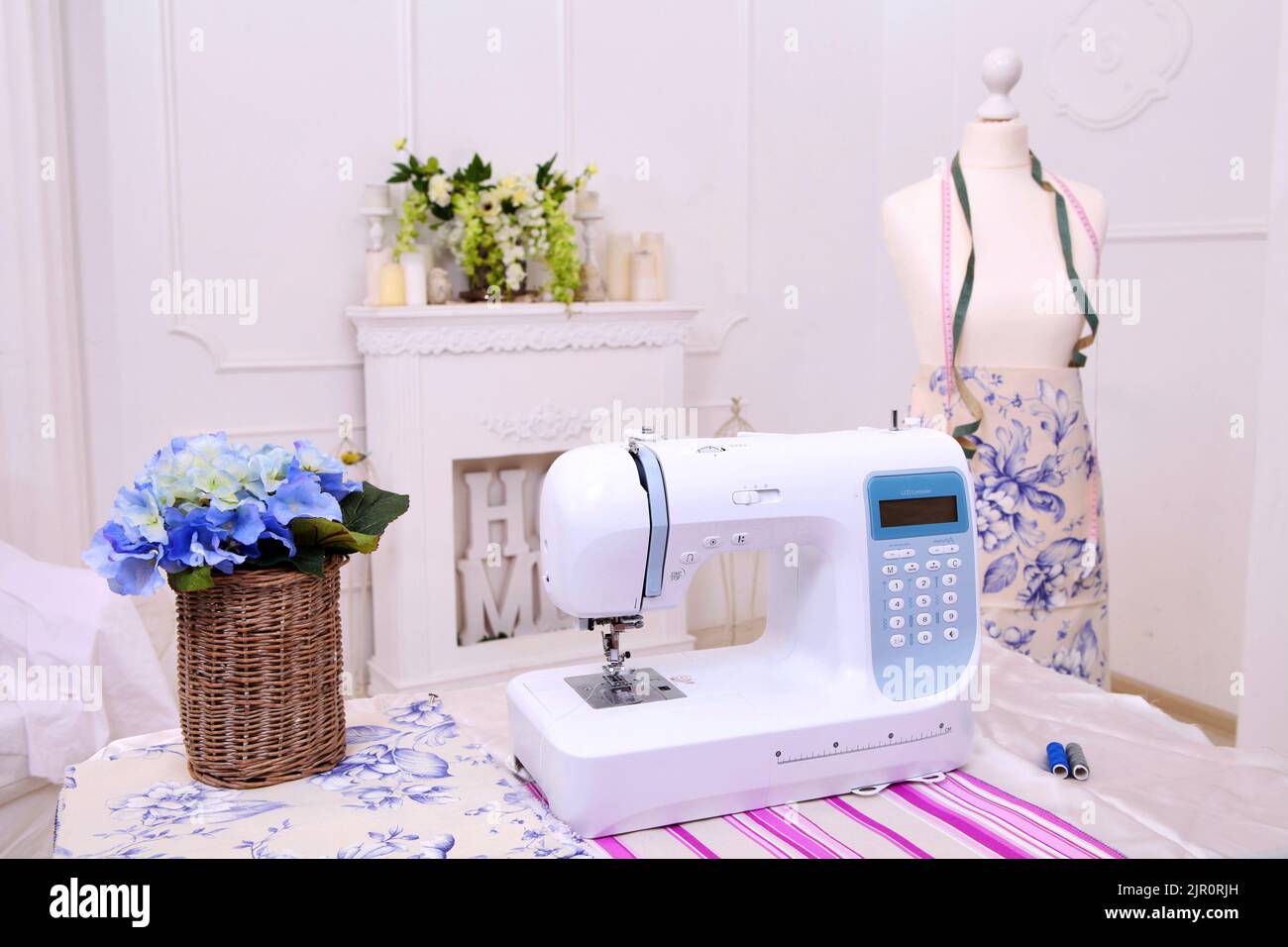 Composition from a sewing machine. Mannequin, flowers on a retro table and threads. Sewing supplies and composition with a sewing machine in the inter Stock Photo