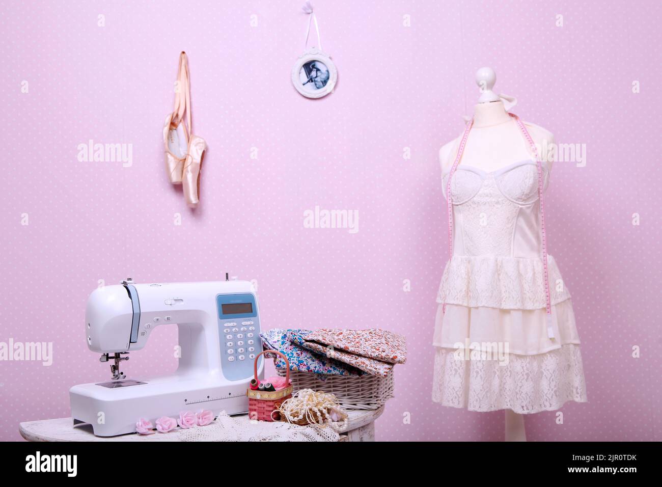 Composition from a sewing machine. Mannequin, flowers on a retro table and threads. Sewing supplies and composition with a sewing machine in the inter Stock Photo