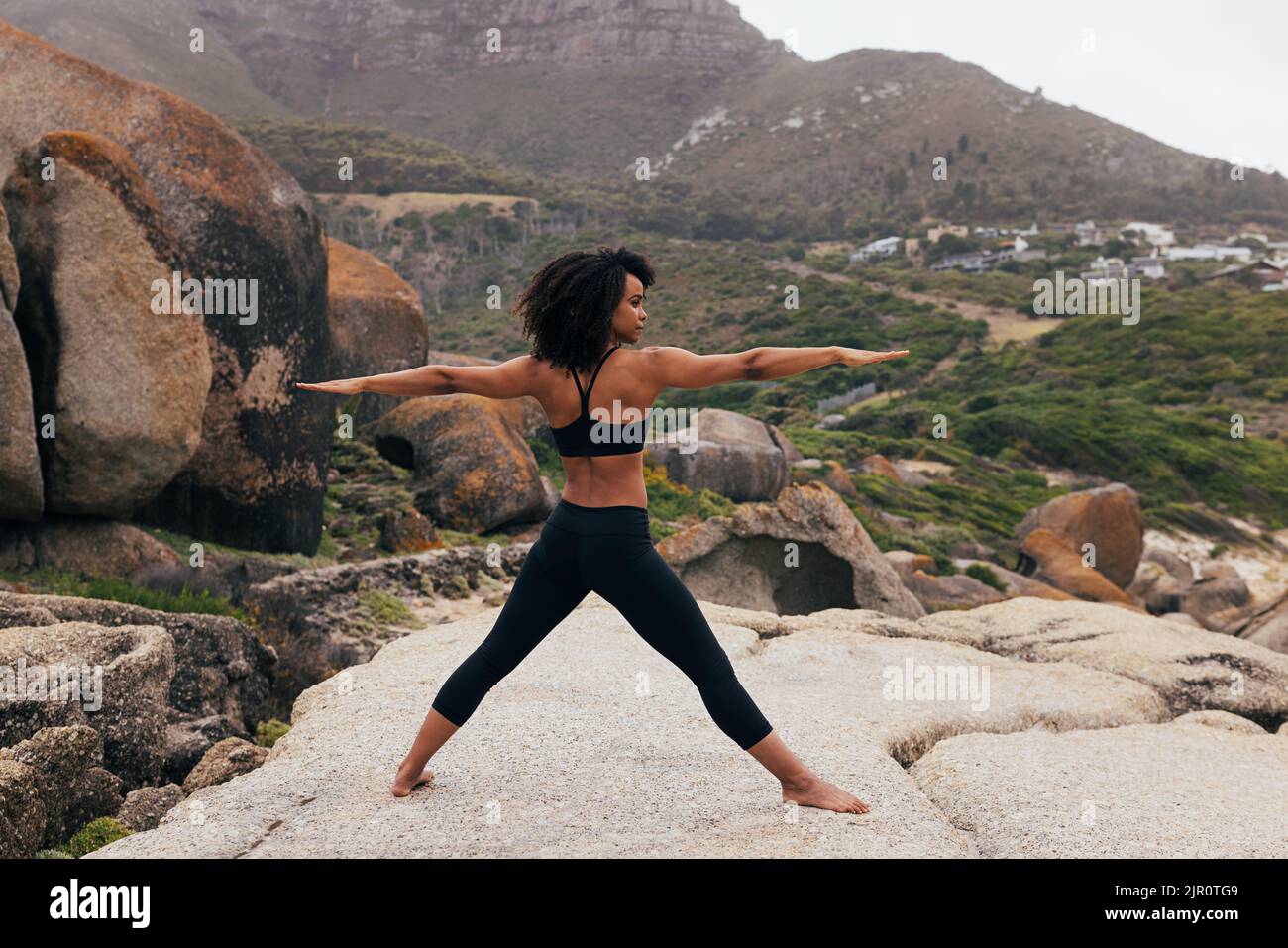 Barefoot woman practicing yoga exercises outdoors while standing on a