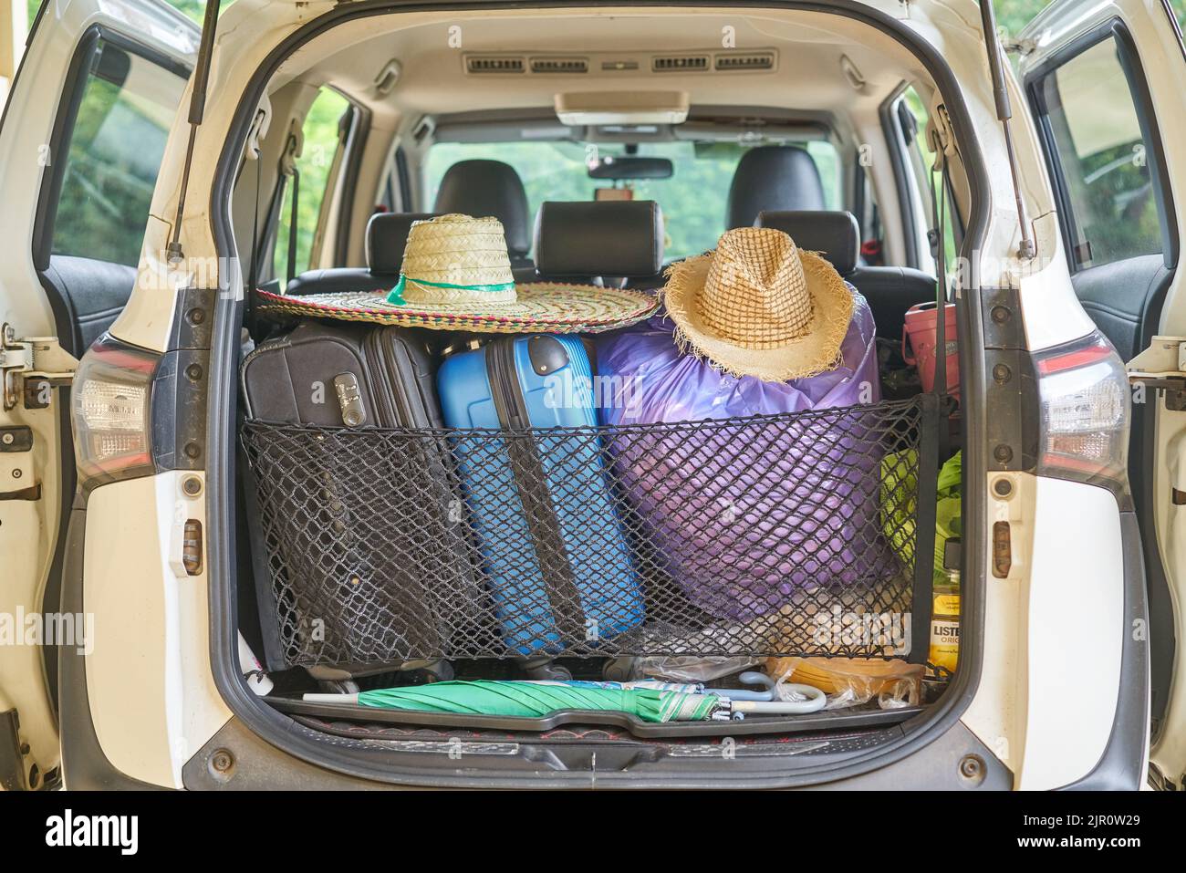 A car packed ready for travel, with sun hats and suitcases. Stock Photo