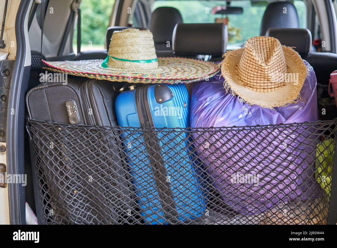 A car packed ready for travel, with sun hats and suitcases. Stock Photo
