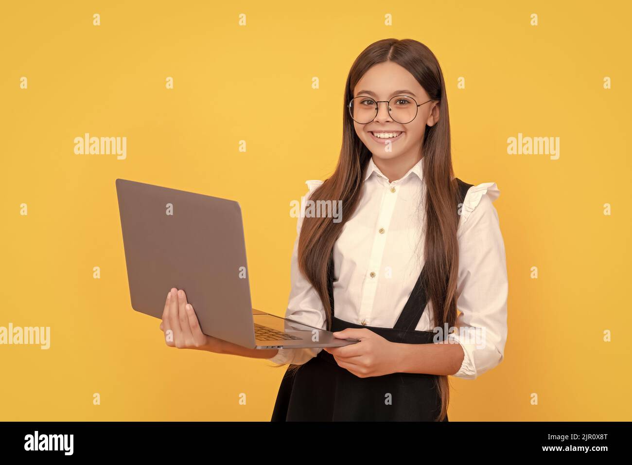 happy child in school uniform and glasses study on laptop, back to