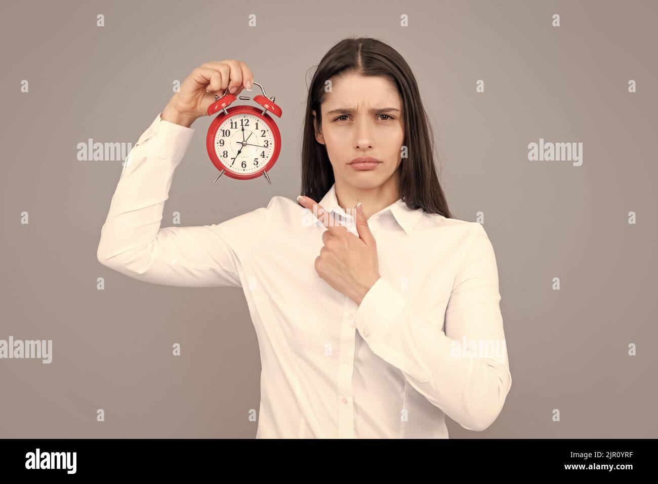 Surprised woman holding alarm watch. Isolated portrait. Stock Photo