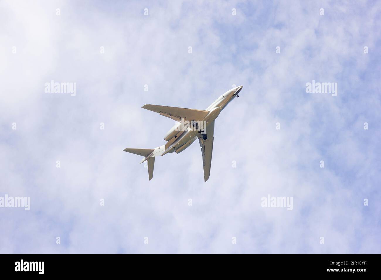 A portrait of a private plane flying low in a cloudy sky. The jet plane