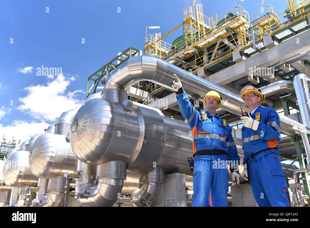teamwork: group of industrial workers in a refinery - oil processing equipment and machinery Stock Photo