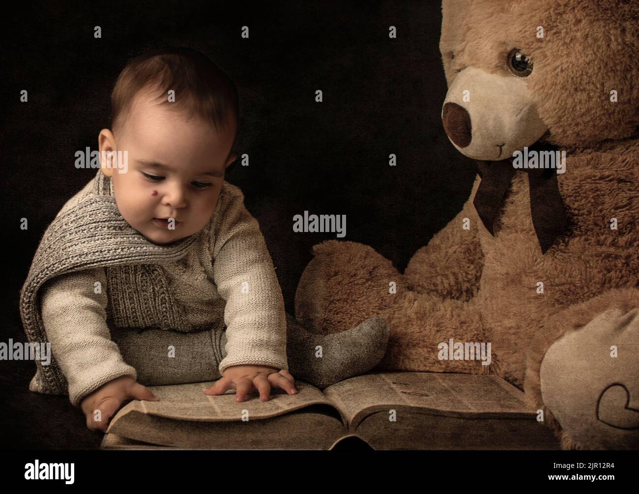 seven months old baby wearing a scraf reading to teddy bear. Dreammy book imagery Stock Photo