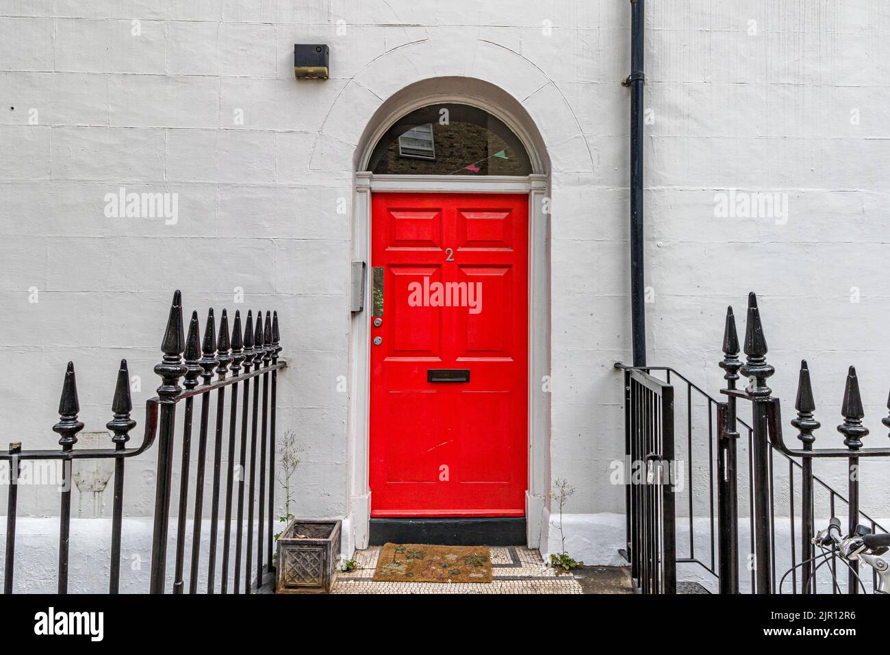 A white painted house with a red front door with a fanlight window arch