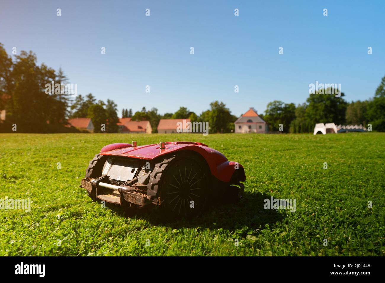 Red robotic lawn mower mows the grass on the lawn. Stock Photo