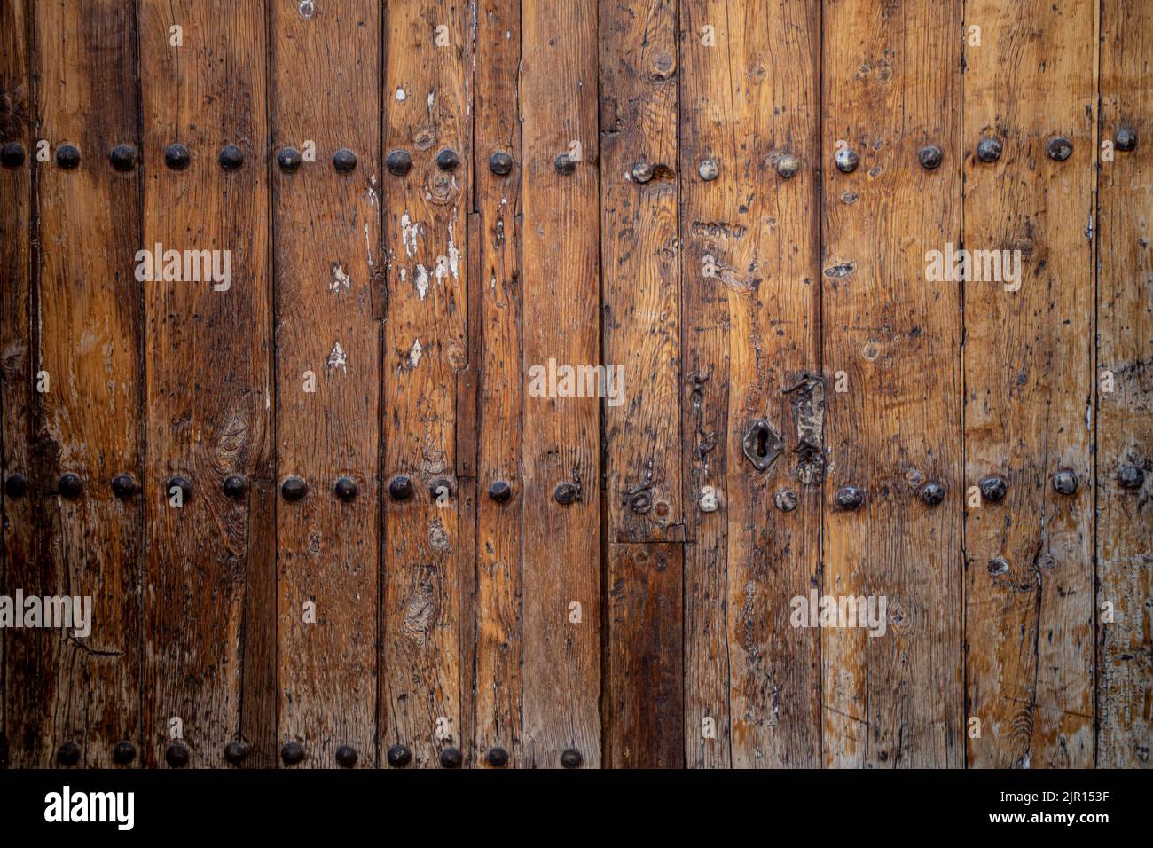 Antique weathered double leaf door with metal knockers and decorations on dark natural wood Stock Photo