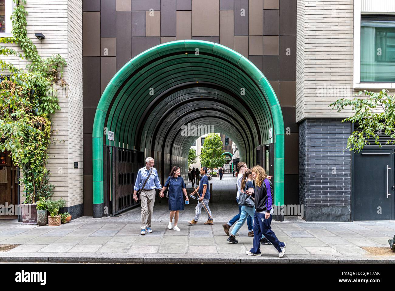 People walking past the turquoise green ceramic tunnel on  Rathbone Square , Fitzrovia, London W1 Stock Photo