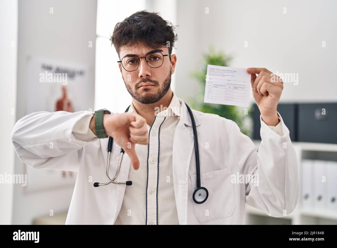Hispanic doctor man with beard holding covid record card with angry ...
