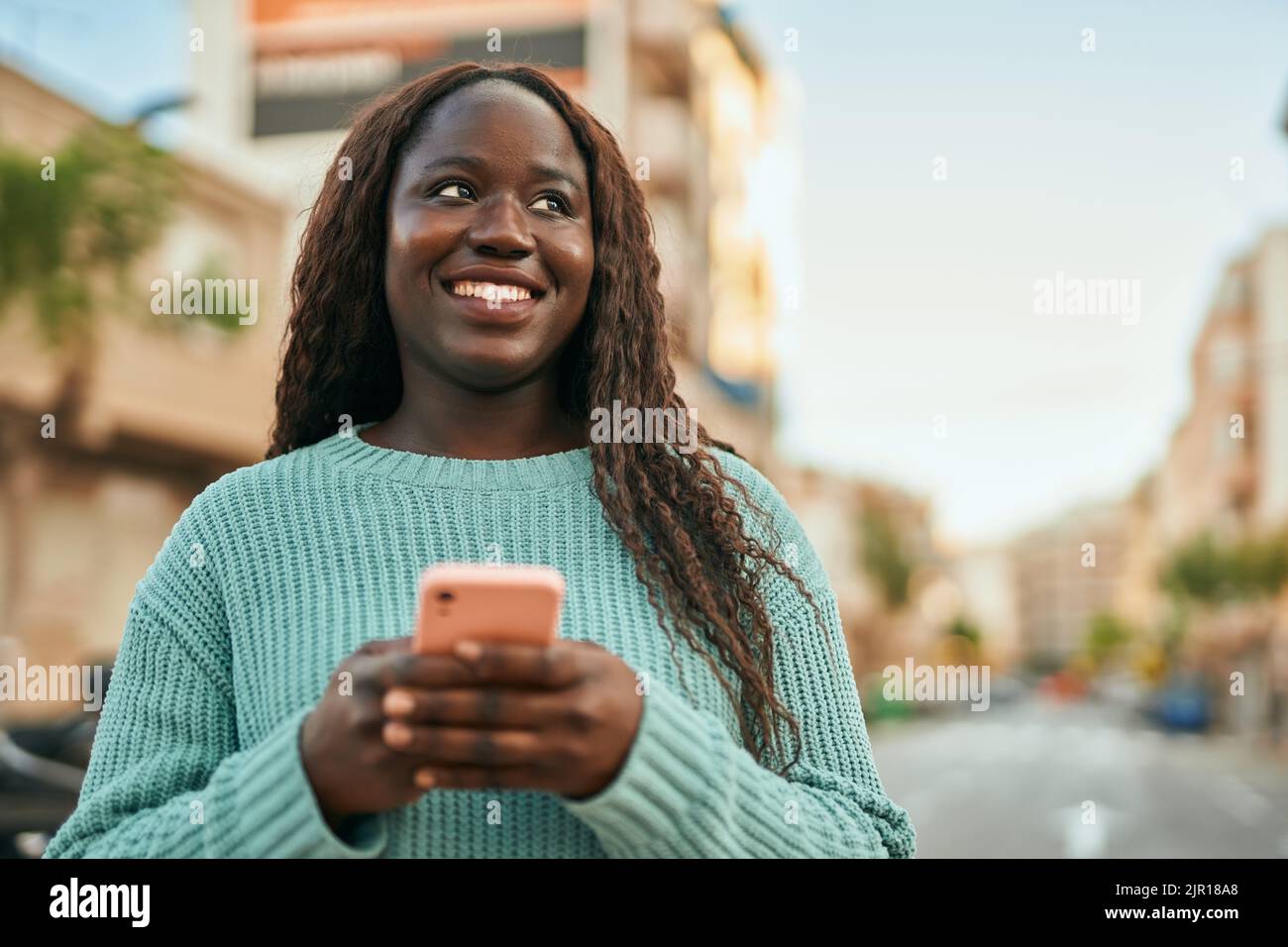 Young african woman smiling happy using smartphone at the city Stock ...