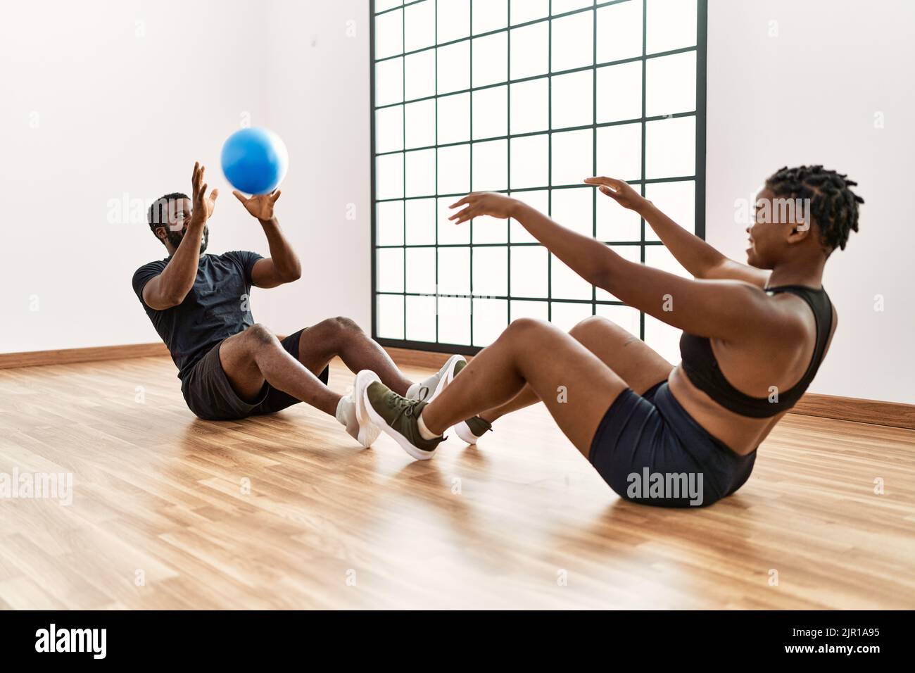 Young african american sporty couple doing abs exercise using ball at