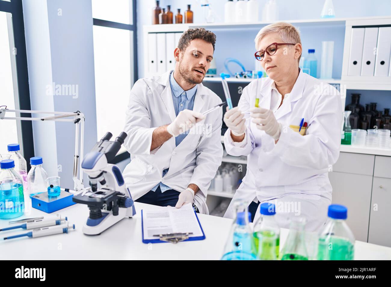 Mother and son scientist partners holding test tubes writing on