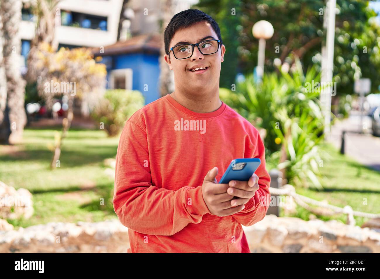 Down syndrome man smiling confident using smartphone at park Stock Photo