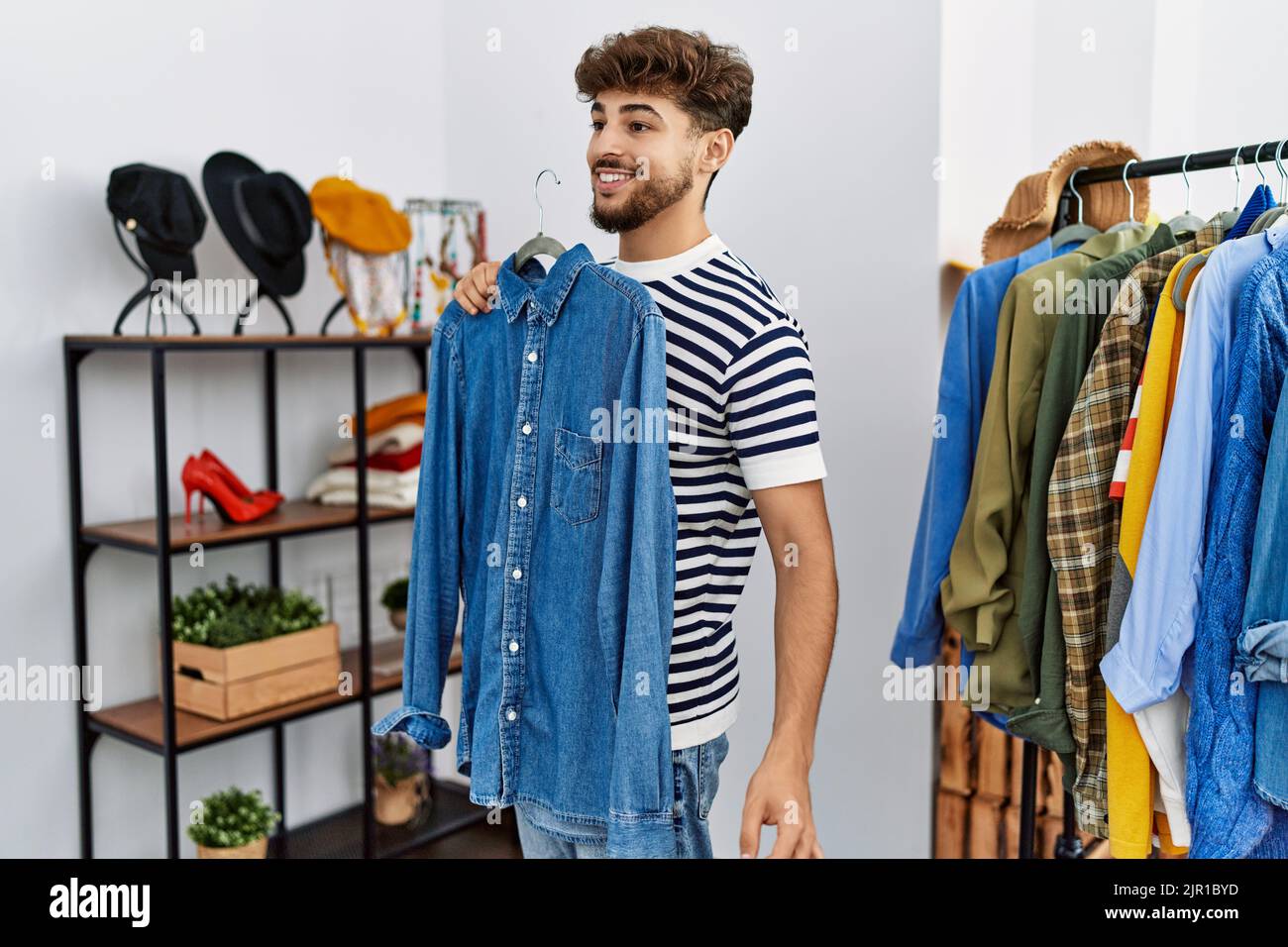 Young arab man customer holding shirt shopping at clothing store Stock ...