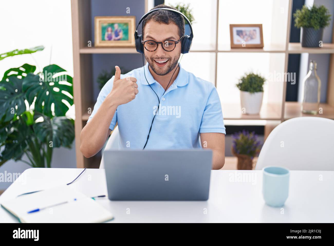 Hispanic man working using computer laptop wearing headphones smiling ...