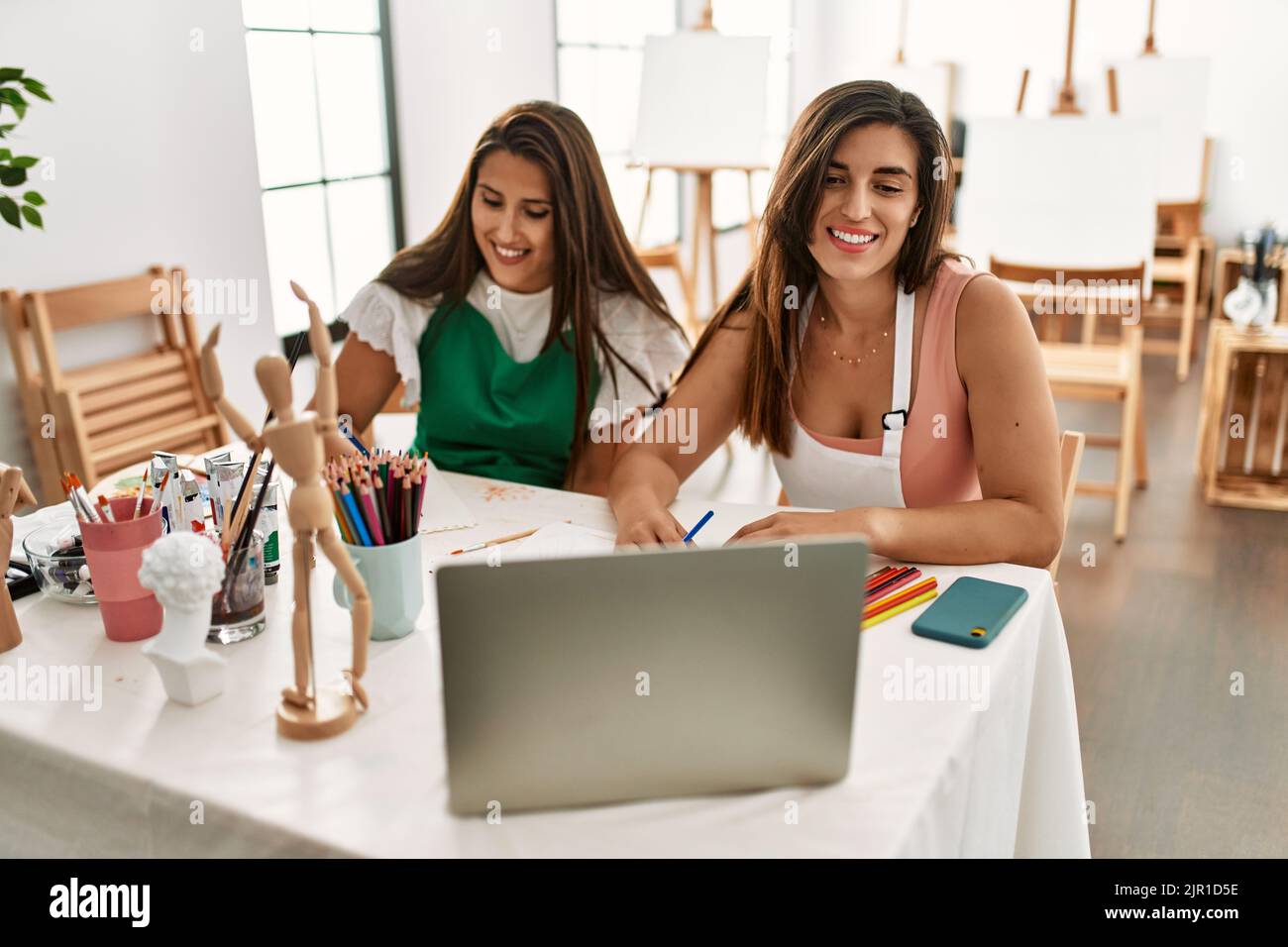 Two latin paint students smiling happy having online paint class at art