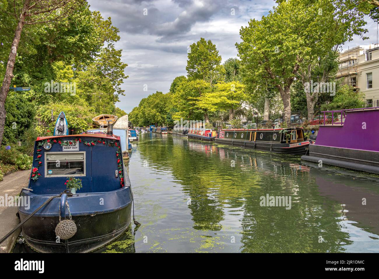 A long line of narrow boats moored along the banks of the Regents Canal, near Little Venice, running alongside Blomfield Road, Maida Vale, London W9 Stock Photo