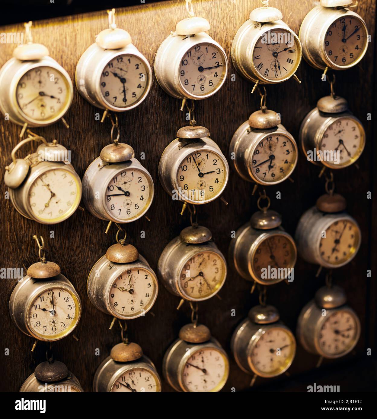 A group of old vintage alarm clocks hanging from each other on the