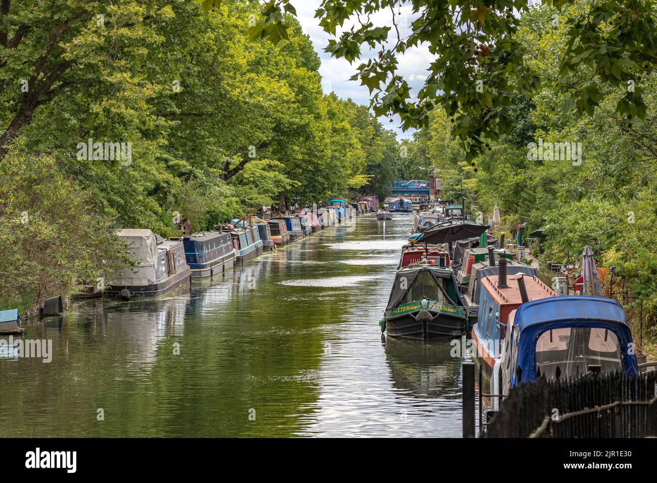 A long line of narrow boats moored along the banks of the Regents Canal, near Little Venice, running alongside Blomfield Road, Maida Vale, London W9 Stock Photo