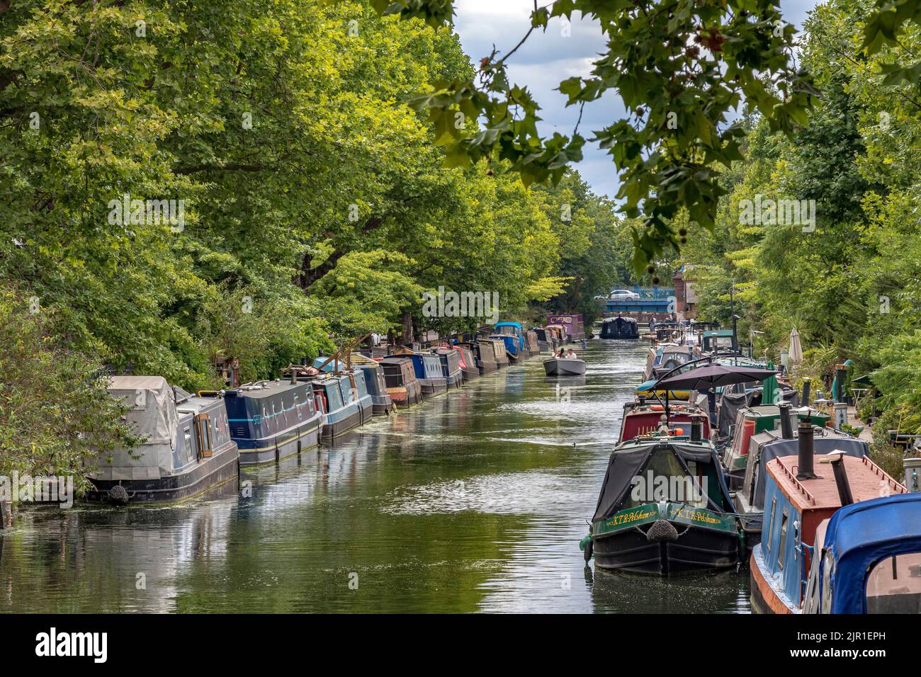 A long line of narrow boats moored along the banks of the Regents Canal, near Little Venice, running alongside Blomfield Road, Maida Vale, London W9 Stock Photo