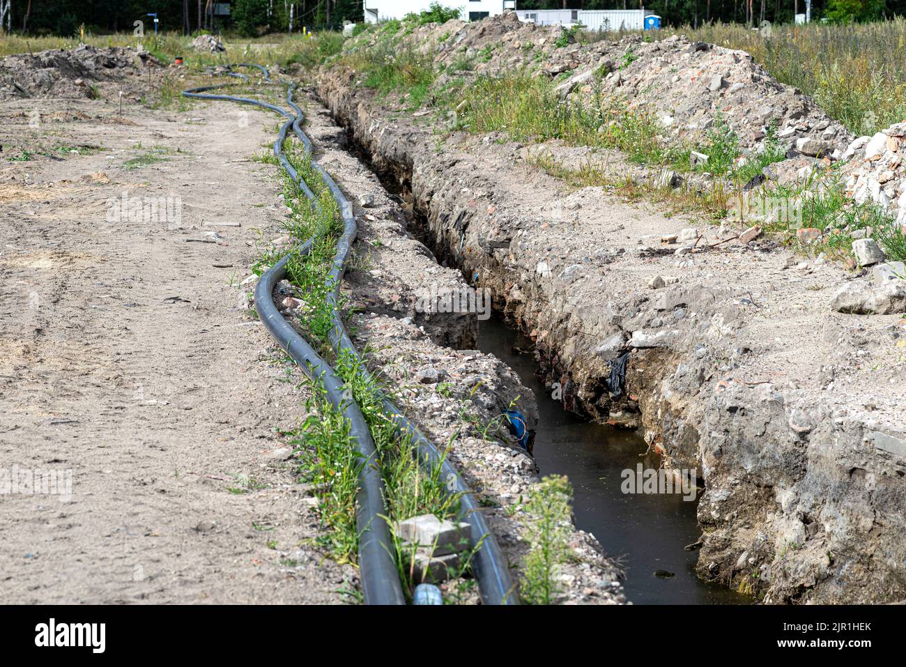 Plastic water pipe lying along the ditch with high groundwater, water