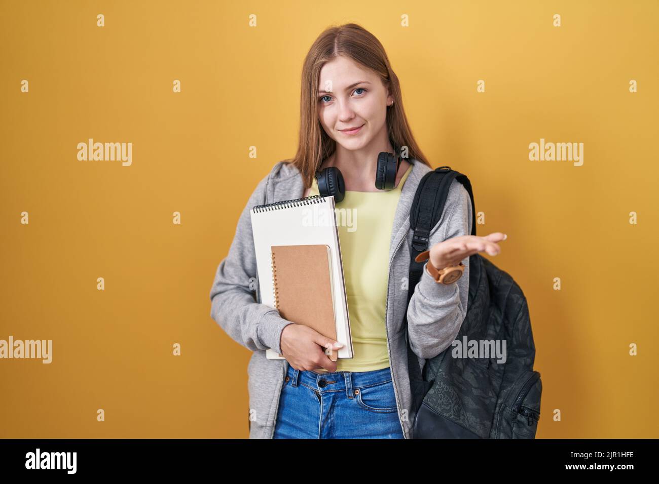 Young caucasian woman wearing student backpack and holding books ...