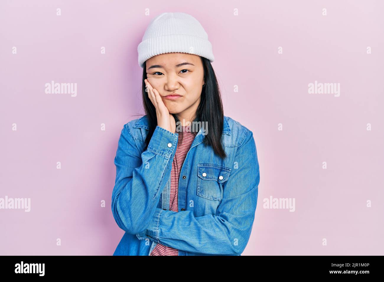 Young chinese girl wearing cute wool cap thinking looking tired and bored with depression problems with crossed arms. Stock Photo