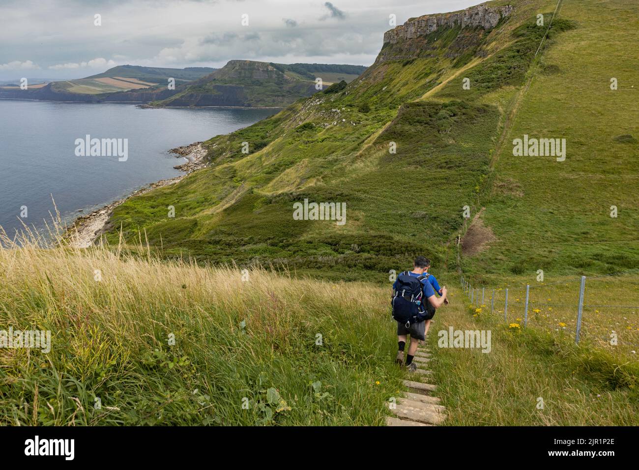 Hikers walk down a steep set of steps on the South West Coast Path in Dorset as they approach Emmetts Hill Stock Photo
