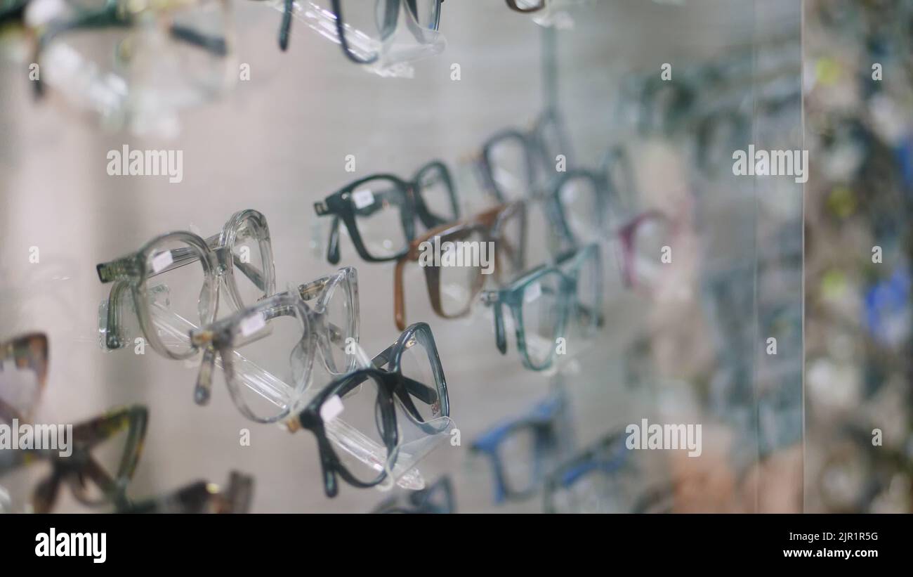 close-up, showcase in optical store, optics, optician retail store, Eyeglasses shop, a lot of glasses, frames, man's hand chooses Fashionable corrective eye glasses, spectacles . High quality photo Stock Photo