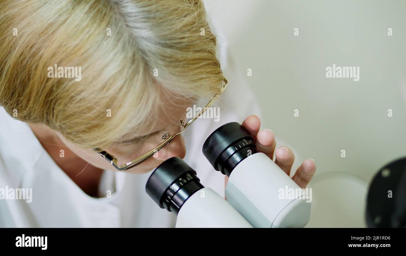 female doctor optometrist, ophthalmologist with non contact tonometer is cheking patient's vision, intraocular pressure at eye clinic or optics store, ophthalmilogical laboratory. High quality photo Stock Photo