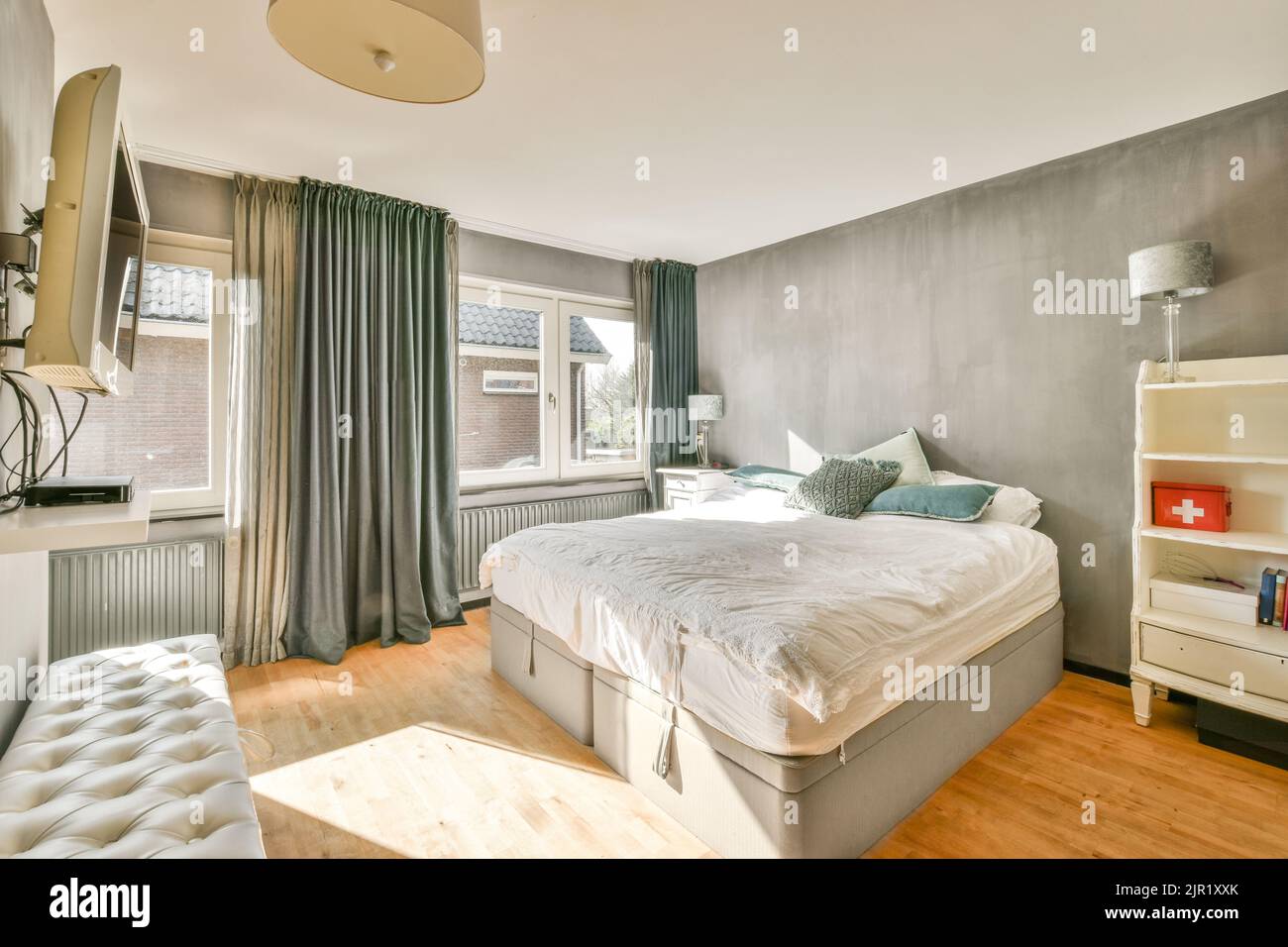 Comfortable bed located near glowing lamp and framed pictures in