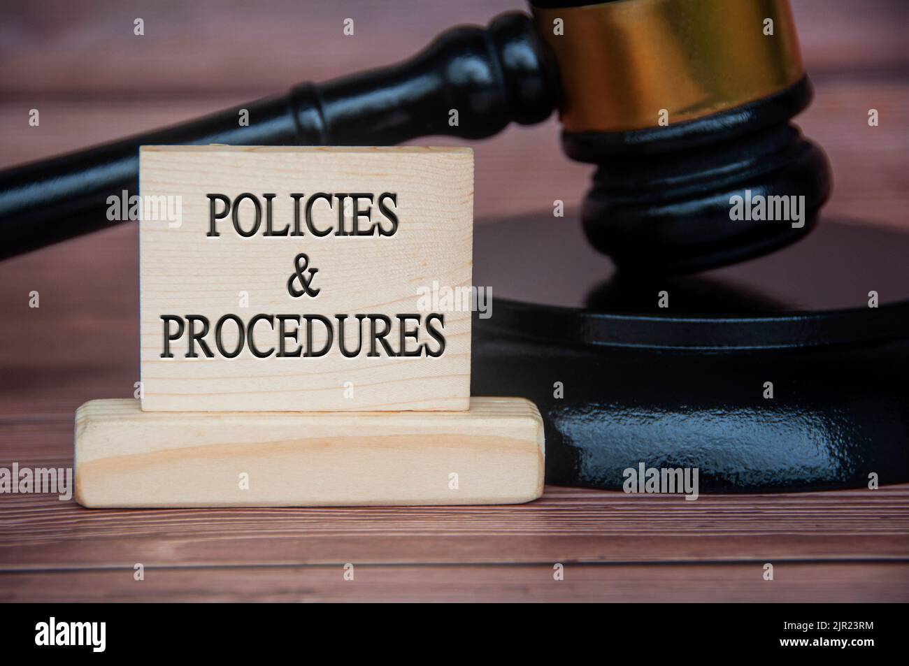 Policies and procedures text engraved on wooden block with gavel background. Policy and procedure concept. Stock Photo