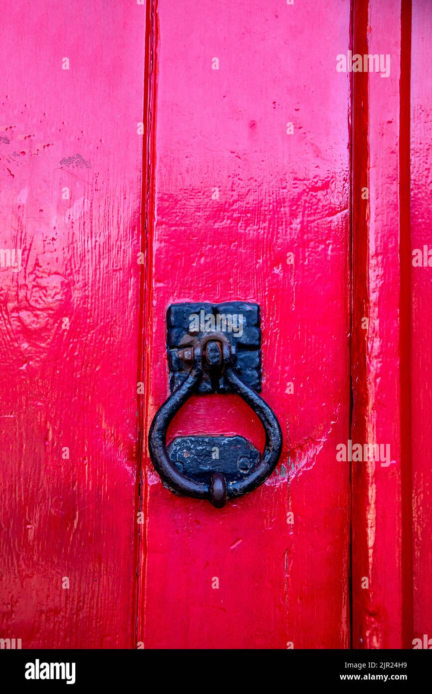 Close up of an red painted door with black door knocker Stock Photo
