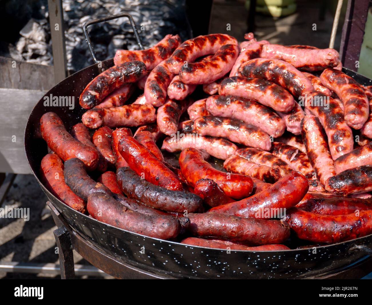 Spanish traditional fresh red and white sausages in the frying pan at the street market Stock Photo