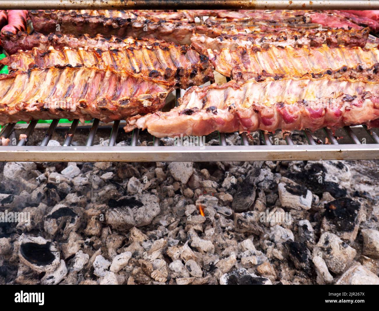 Roasted racks of pork ribs at the charcoal grill. Open fife barbecue. Stock Photo