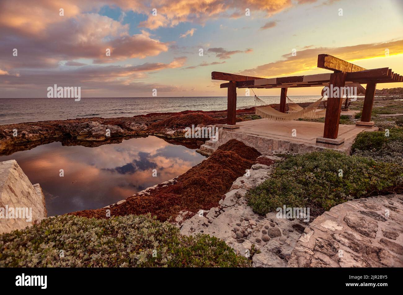 Gazebo with two hammocks below, natural pool and sunset an image that