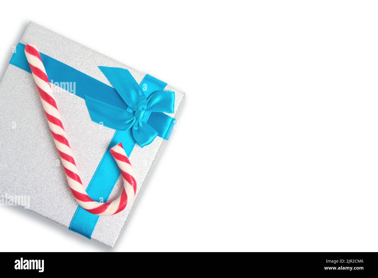 Christmas gift box with blue bow and a red and white candy in form cane ...