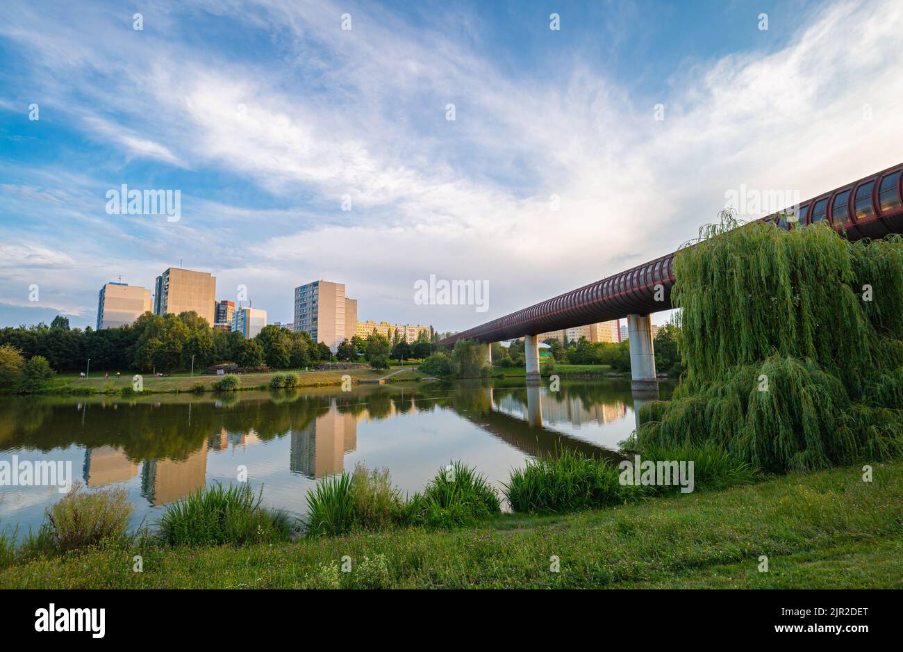 Scenic view of a city park in a suburban area of the city of Prague with Hůrka–Lužiny metro bridge over a lake in the park. Stock Photo
