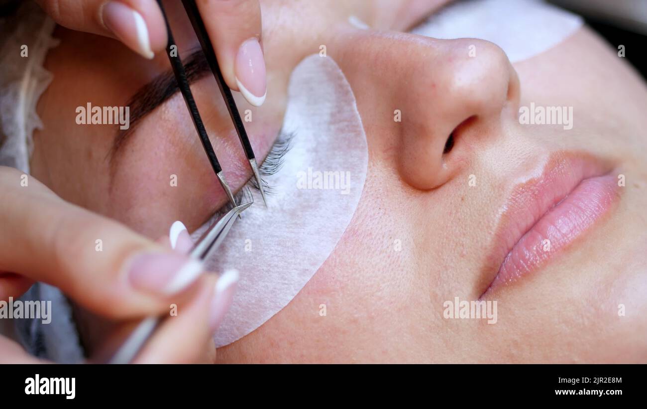 beauty saloon. close-up, procedure for eyelash extension. The master glues each cilium with special glue, works by means of two tweezers. High quality photo Stock Photo