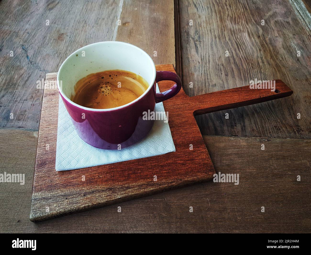 A selective focus shot of Coffee in a purple mug on a wooden tray in Cape Town, South Africa Stock Photo