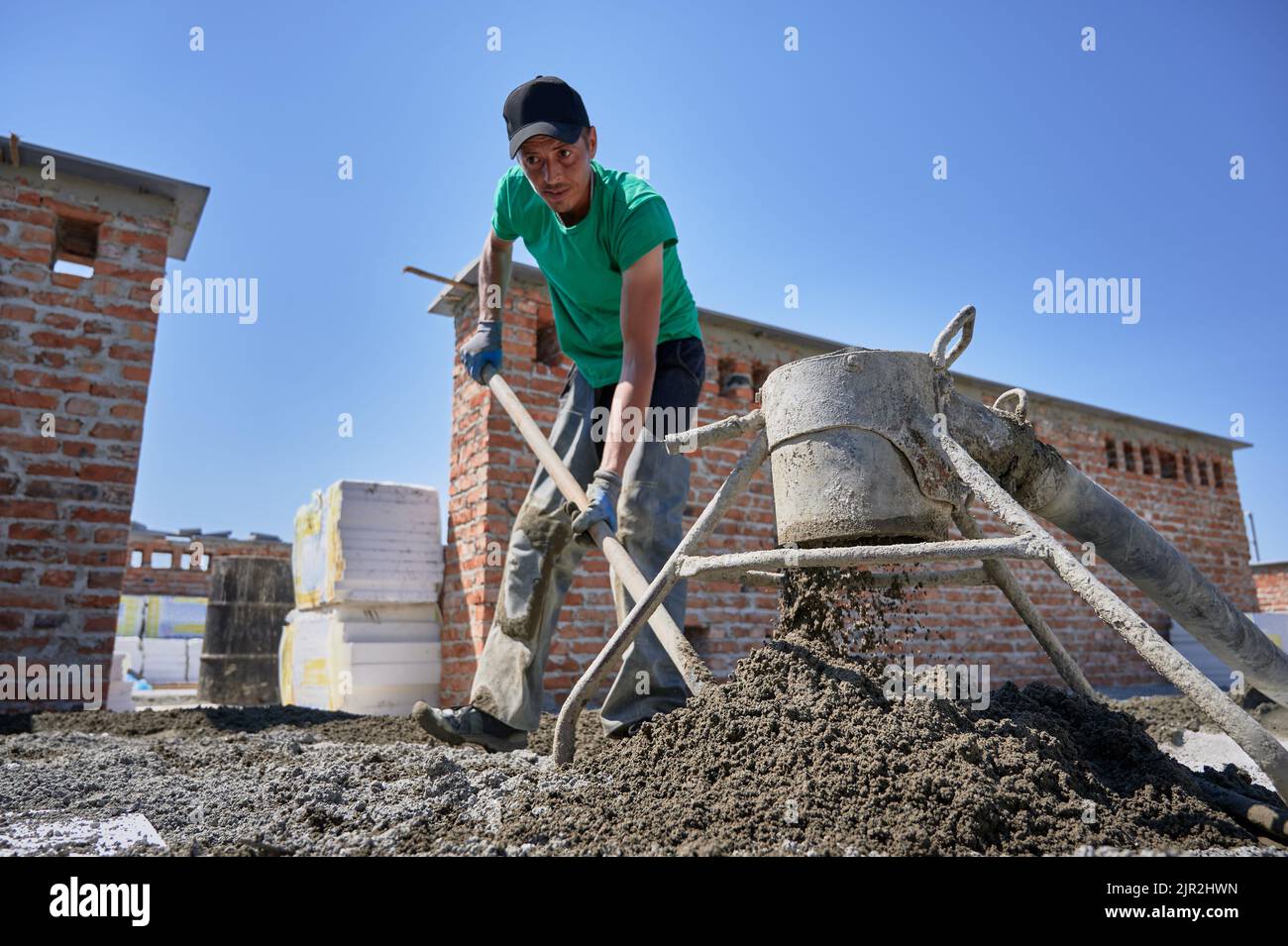 Full length of man builder shoveling sandcement mix while working
